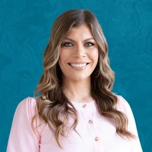 Amber Guillory Smiling In Front Of Blue Background
