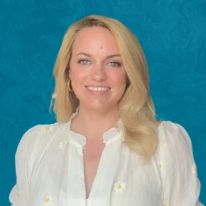 Jessica Collins Smiling In Front Of Blue Background