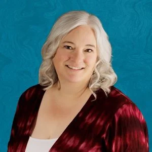 Stacey Willey Smiling In Front Of Blue Background